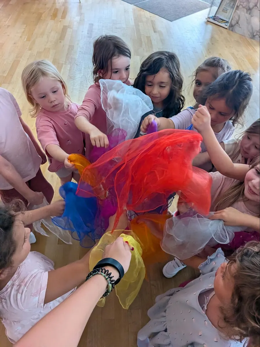 Kinder im Minis-Kurs von LaTinas Dancestudio spielen mit bunten Tüchern im Tanzsaal